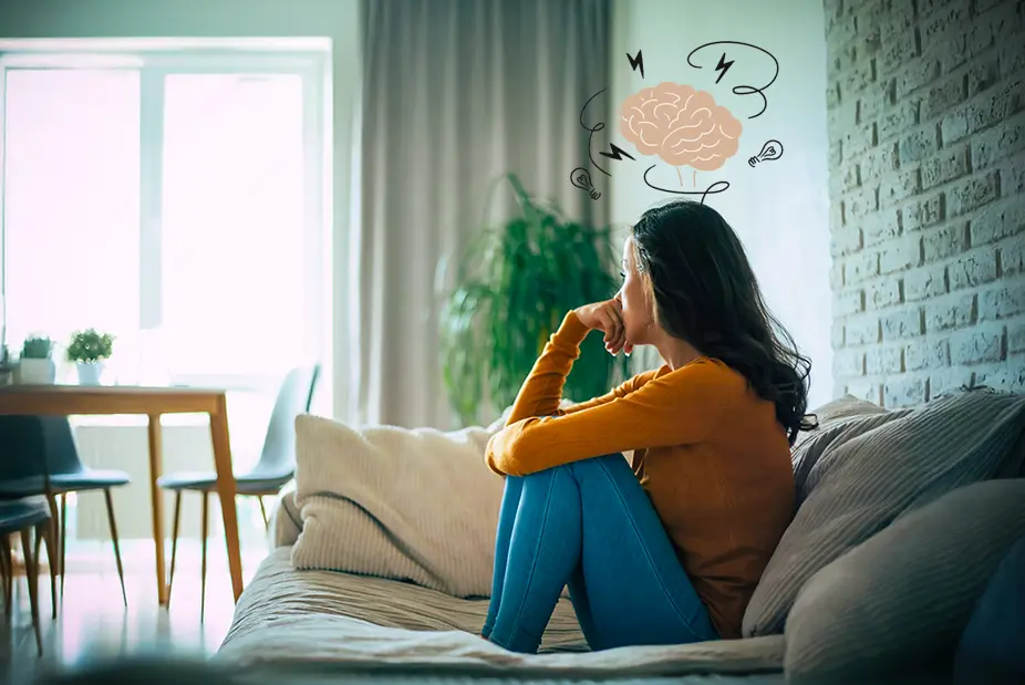 Woman sitting thoughtfully on a couch with an illustrated brain above her head, representing anxiety, depression, or ADHD-related mental health challenges.